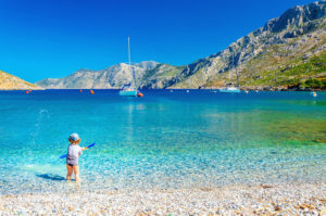 Amazing sea bay on Greek Island with a small boy at play on the seashore, Greece