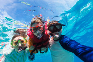 Underwater portrait of family snorkeling together at clear tropical ocean